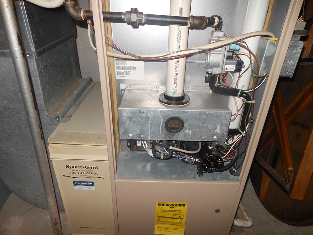 Central air conditioning unit with Space-Gard air cleaner, ducts, and energy efficiency guide in residential setting.