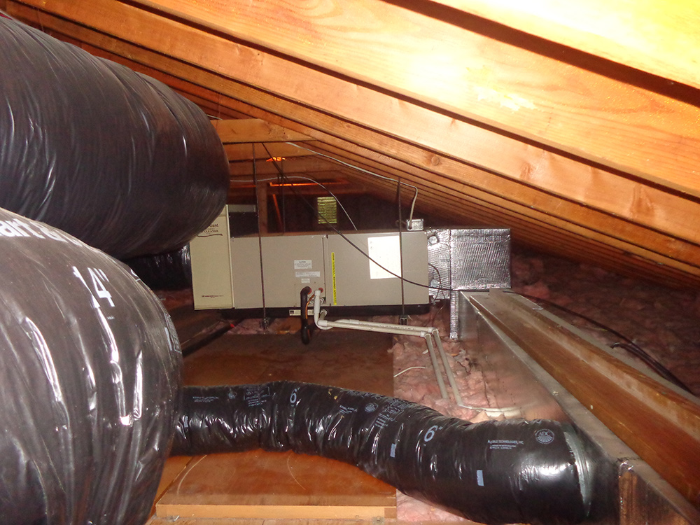 Attic central air conditioning system with ductwork and insulated pipes.