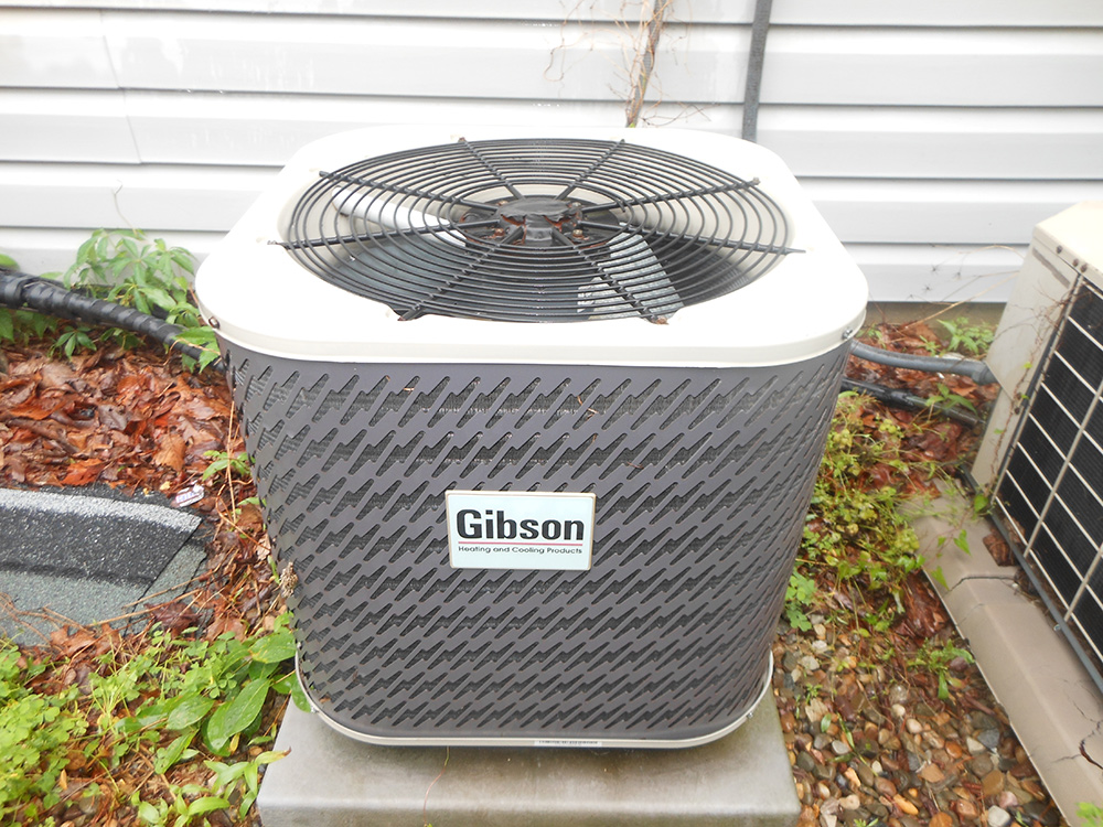Outdoor central air conditioning unit by Gibson, efficient cooling system for residential use, installed next to a house.