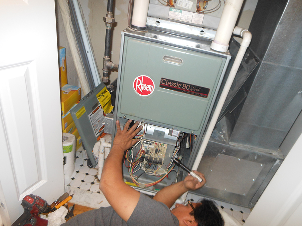 Technician repairing Rheem Classic 90 Plus central air conditioning unit in utility room.