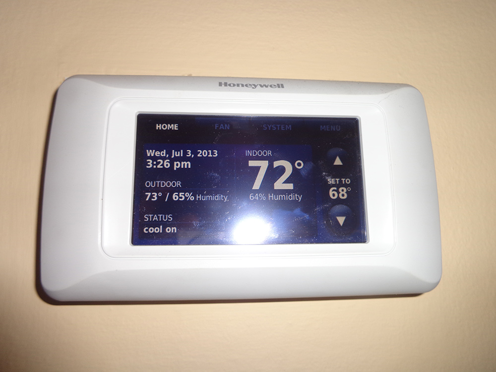 Digital thermostat displaying indoor temperature and humidity, central air conditioning control, energy efficiency.