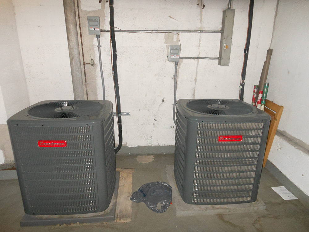 Central air conditioning units in basement, Goodman brand, industrial HVAC system installation.