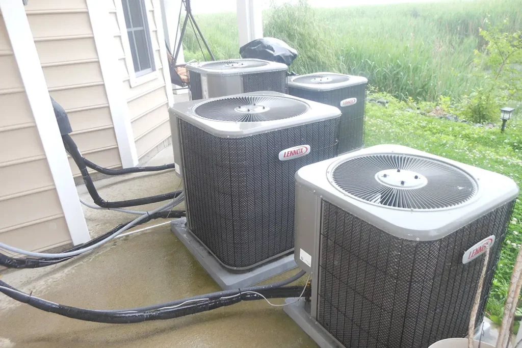 Outdoor Lennox air conditioning units installation on concrete pad near house with garden background.