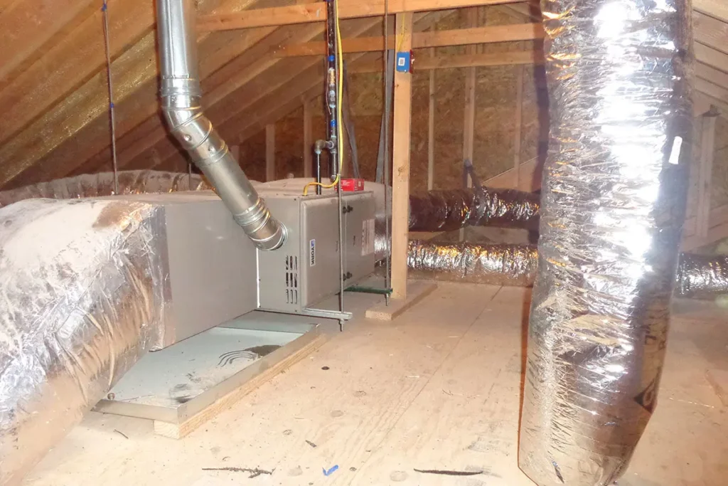 Attic HVAC system installation with insulated ductwork and furnace unit for efficient home heating and cooling.