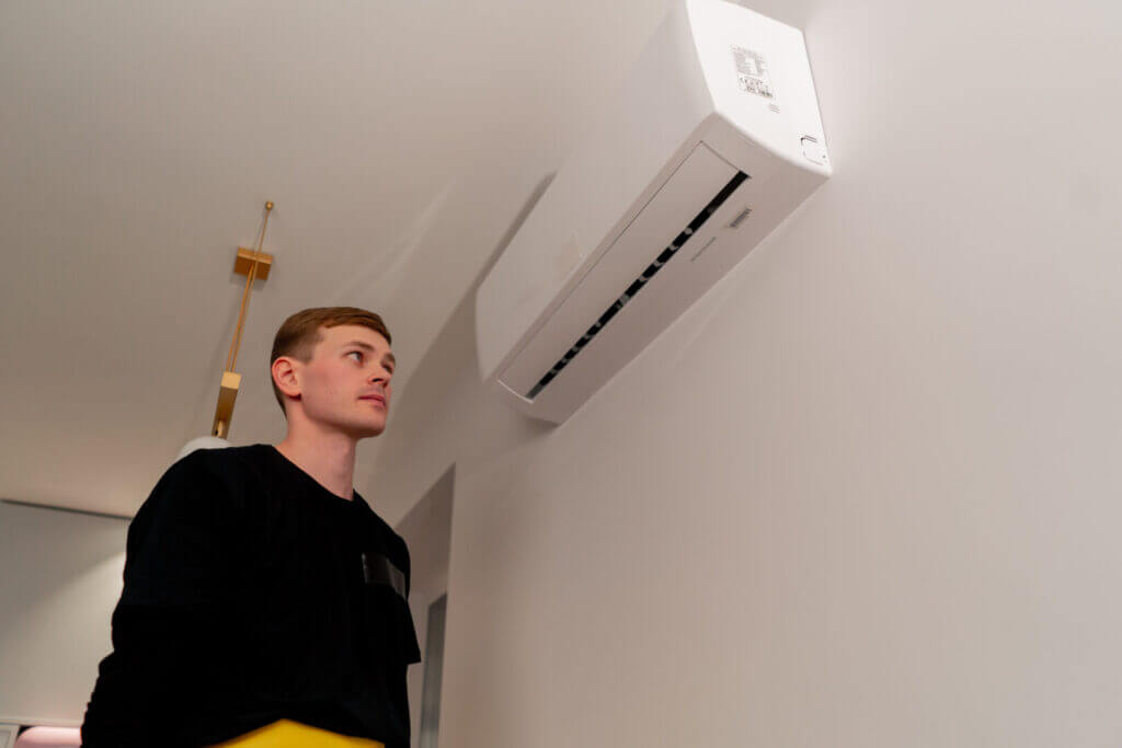 Cleaner preparing to open air conditioner for filter maintenance in modern apartment. Ideal for HVAC and home care topics.