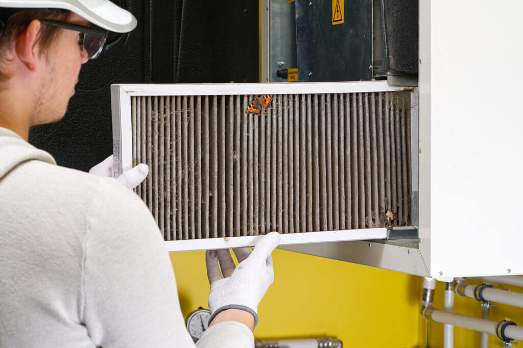 Person replacing HVAC filter in home central ventilation system.