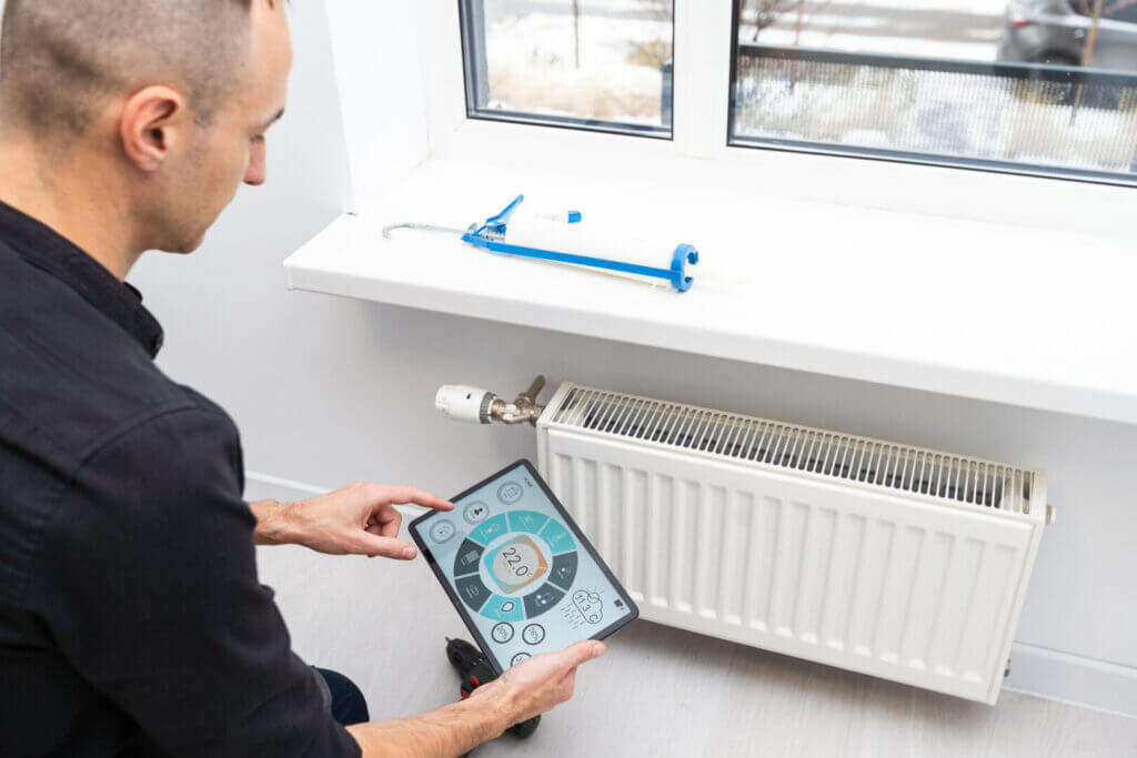 Technician using tablet to inspect heating system in boiler room, ensuring optimal performance and energy efficiency.